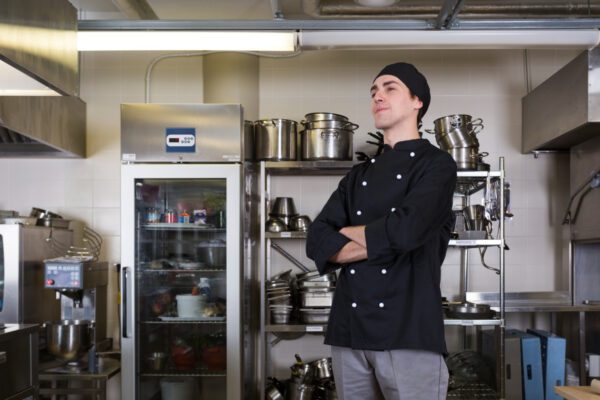 Kaip išsirinkti restoranų įrangą: nuo virtuvės iki baro zonos Profesionali restorano virtuvės įranga su šefu prie viryklės ir veikiančia baro zona, atspindinti sklandų darbo procesą.