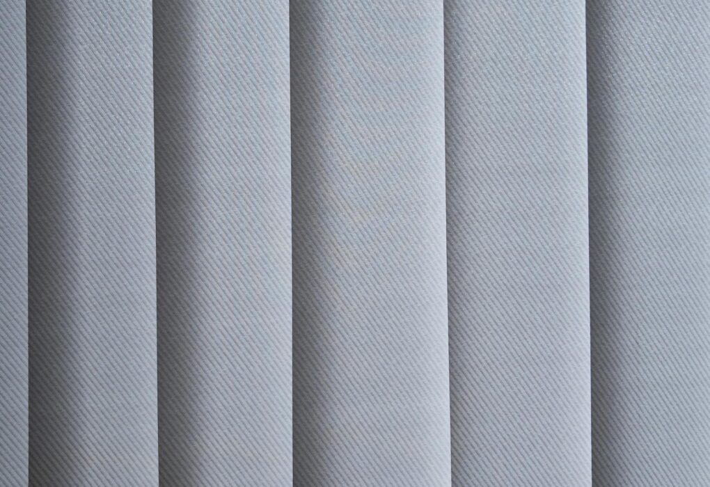 Modernūs kasetiniai roletai ant plastikinio lango rėmo šviesiame kambaryje.